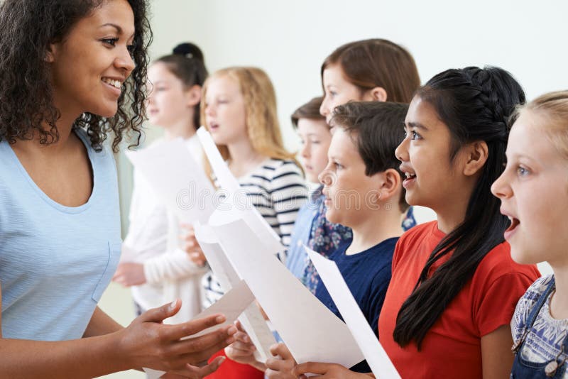 Enfants dans le choeur d'école encouragé par le professeur image stock Enfants dans le choeur d'école encouragé par le professeur image stock