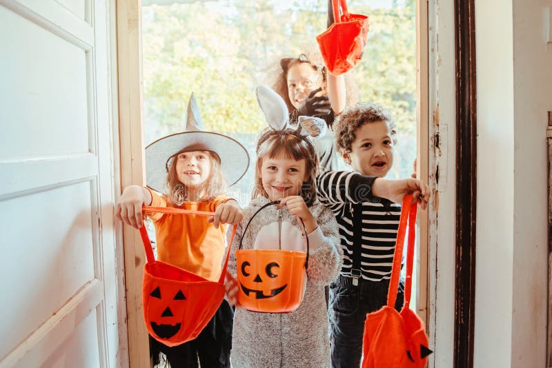 Children in Halloween costumes, trick or treating in front of an old house. Children in Halloween costumes, trick or treating in front of an old house