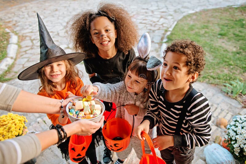 Children in Halloween costumes, trick or treating in front of an old house. Children in Halloween costumes, trick or treating in front of an old house