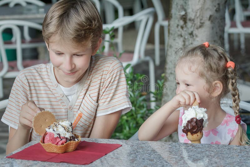 Enfants de garçon et de fille appréciant leur crème glacée italienne dans le gelateria image stock
