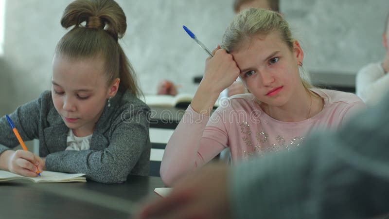 Enfants de l'école primaire assis en classe et écoutant un enseignant en cours banque de vidéos
