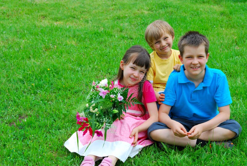 Enfants de sourire sur l'herbe photographie stock libre de droits Enfants de sourire sur l'herbe photographie stock libre de droits