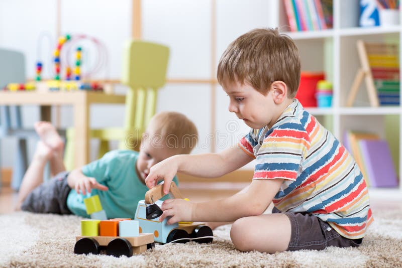 Enfants en bas âge de garçons d'enfants jouant avec la voiture de jouet à l'intérieur photographie stock Enfants en bas âge de garçons d'enfants jouant avec la voiture de jouet à l'intérieur photographie stock