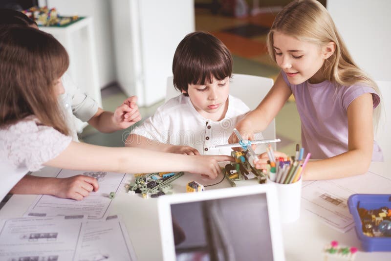 Enfants gais créant le robot pendant la leçon photos libres de droits Enfants gais créant le robot pendant la leçon photos libres de droits