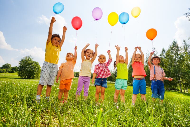 Enfants heureux avec des ballons et des bras dans le ciel photos libres de droits Enfants heureux avec des ballons et des bras dans le ciel photos libres de droits