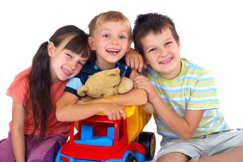 A view of three smiling, happy children as they pose together with a toy dump truck and stuffed animal. Isolated on white background. A view of three smiling, happy children as they pose together with a toy dump truck and stuffed animal. Isolated on white background