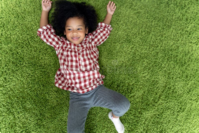 Enfants heureux d'enfants souriant et s'étendant sur la moquette verte dans le salon à la maison photo libre de droits Enfants heureux d'enfants souriant et s'étendant sur la moquette verte dans le salon à la maison photo libre de droits