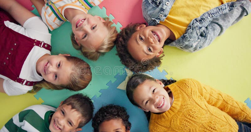 Enfants heureux et allongé en cercle sur matelas à l'école avec vue de dessus pour se détendre amusant et portrait en classe. enfa banque de vidéos