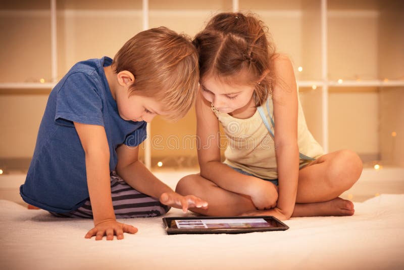 Enfants heureux jouant sur le comprimé images stock Enfants heureux jouant sur le comprimé images stock