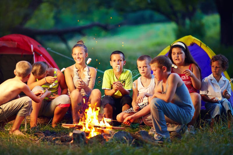 Enfants heureux rôtissant des guimauves sur le feu de camp images stock Enfants heureux rôtissant des guimauves sur le feu de camp images stock