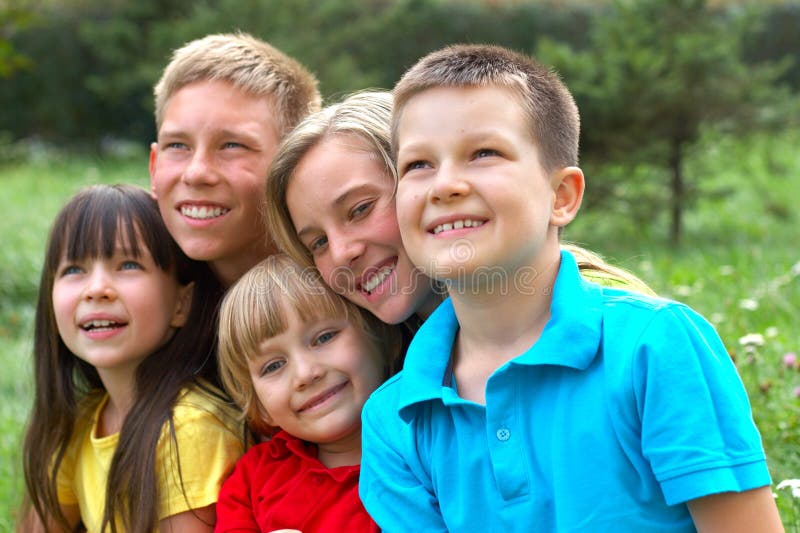 Portrait of five smiling children in a natural outdoor setting, heads close together. Portrait of five smiling children in a natural outdoor setting, heads close together.