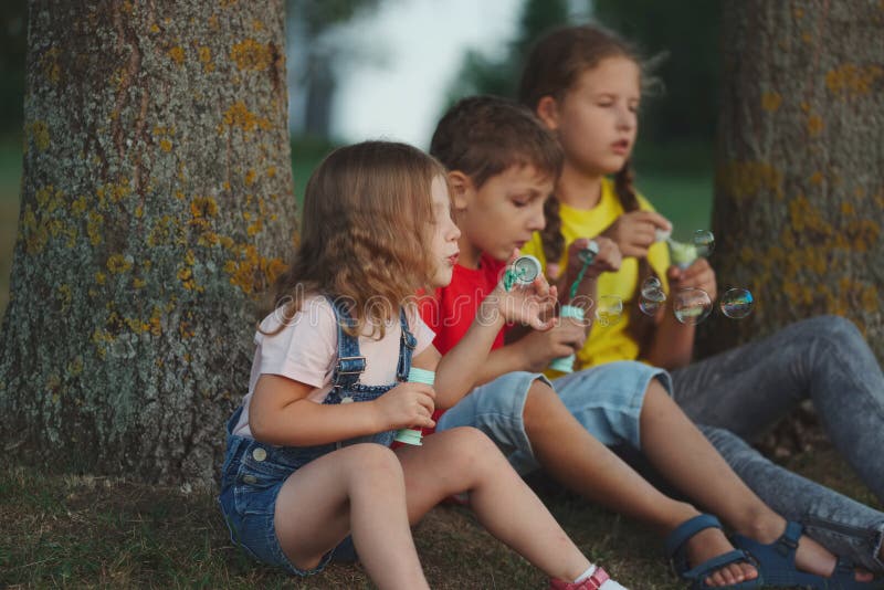 Enfants jouant avec des bulles de savon en parc images libres de droits Enfants jouant avec des bulles de savon en parc images libres de droits