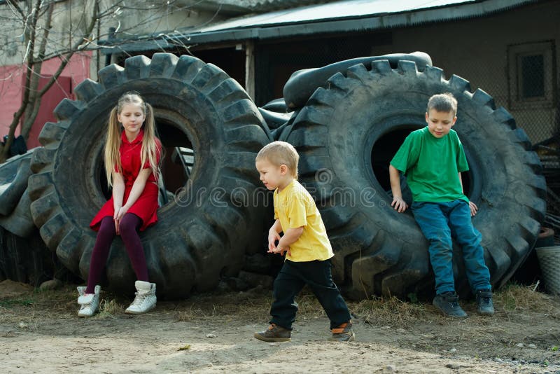 Enfants jouant dans des pneus d'entrepôt de ferraille image libre de droits Enfants jouant dans des pneus d'entrepôt de ferraille image libre de droits
