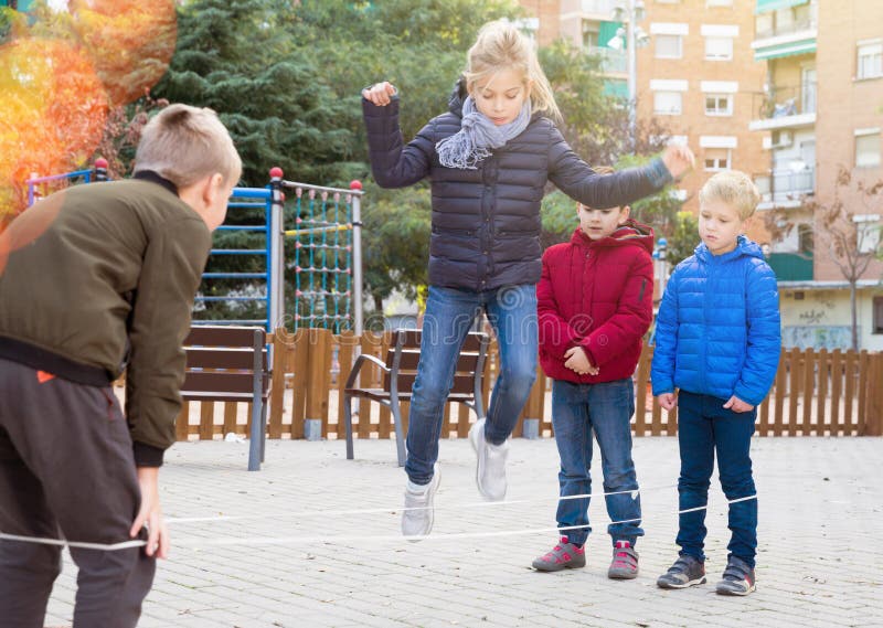 Groupe D'enfants Enjoués Sauter Ensemble Avec La Corde À Sauter Sur Terrain  De Jeu Urbain Banque D'Images et Photos Libres De Droits. Image 64998473