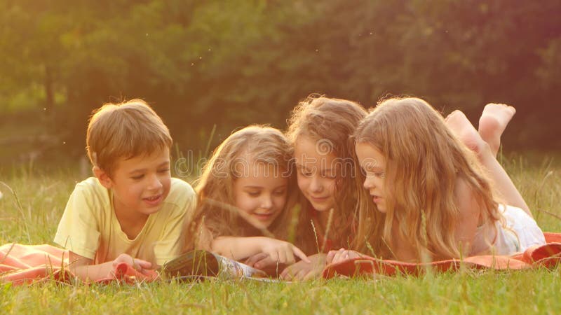 Enfants mignons lisant un livre pendant l'été de jardin ensemble par beau jour Fin vers le haut