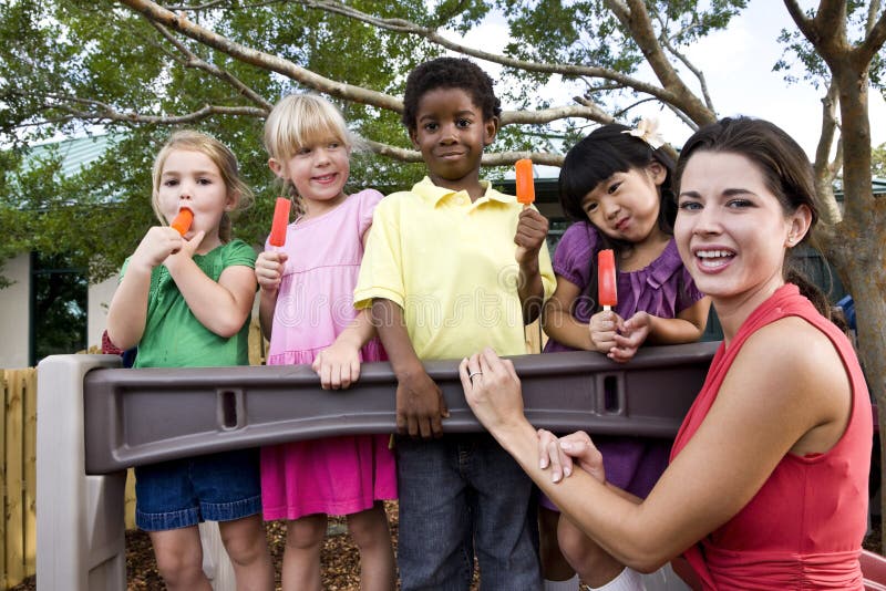 Enfants préscolaires sur la cour de jeu avec le professeur photo stock Enfants préscolaires sur la cour de jeu avec le professeur photo stock