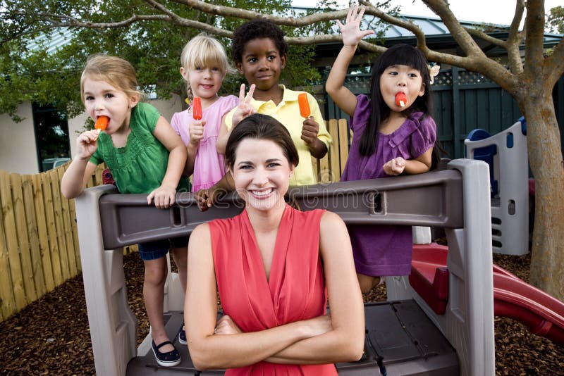 Enfants préscolaires sur la cour de jeu avec le professeur photo stock Enfants préscolaires sur la cour de jeu avec le professeur photo stock