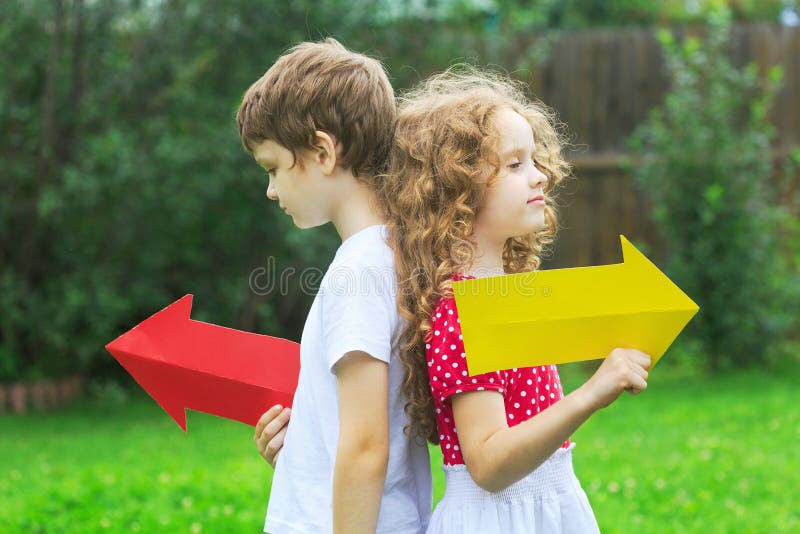 Enfants tenant la flèche de couleur se dirigeant juste et à gauche, en été photographie stock libre de droits Enfants tenant la flèche de couleur se dirigeant juste et à gauche, en été photographie stock libre de droits