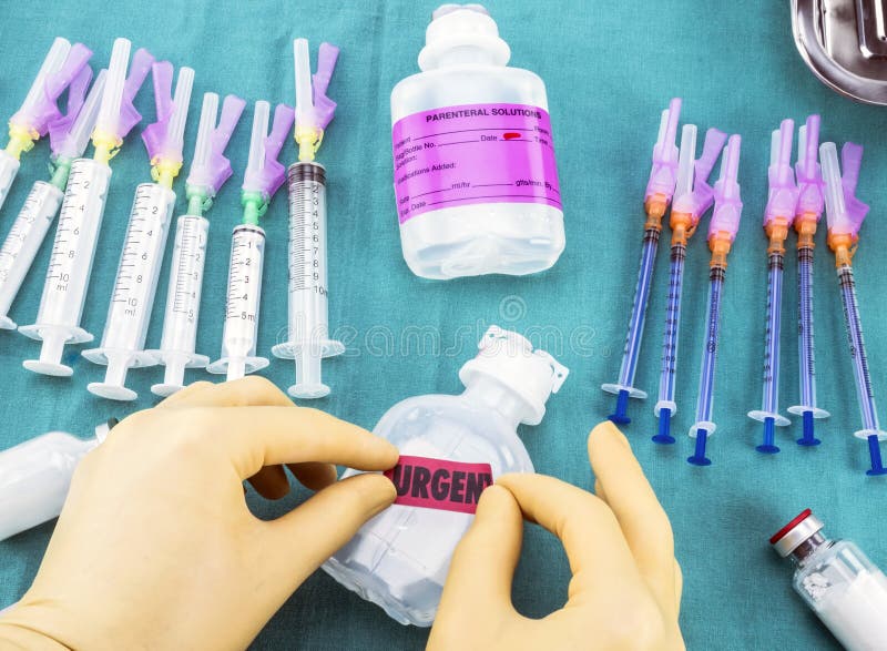 Enfermeira que prepara a medicamentação do hospital, colando a etiqueta urgente na garrafa da medicamentação, imagem conceptual foto de stock Enfermeira que prepara a medicamentação do hospital, colando a etiqueta urgente na garrafa da medicamentação, imagem conceptual foto de stock