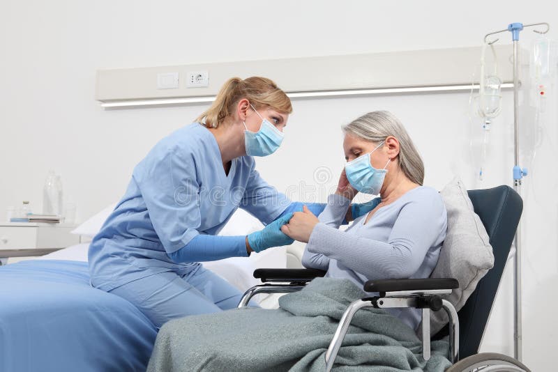 Enfermeira toma conforto mulher idosa em cadeira de rodas usando máscaras médicas de proteção cirúrgica no conceito de isolamento
