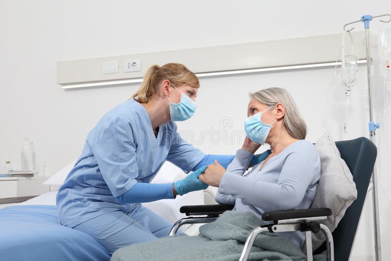 Enfermeira toma conforto mulher idosa em cadeira de rodas usando máscaras médicas de proteção cirúrgica no conceito de isolamento