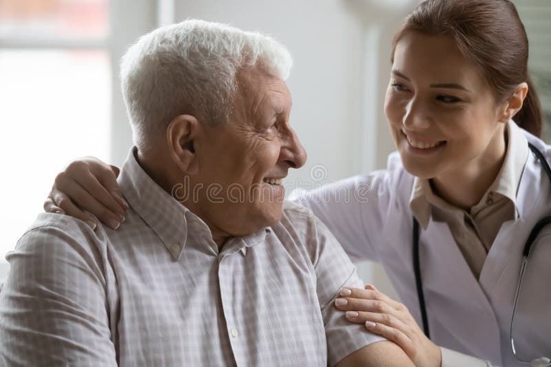 Enfermero femenino positivo que cuida a paciente masculino de mayor edad imagenes de archivo