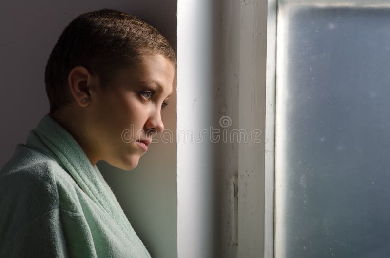 Enfermo de cáncer joven que se coloca delante de ventana del hospital foto de archivo Enfermo de cáncer joven que se coloca delante de ventana del hospital foto de archivo
