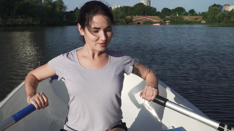Enfileiramento bonito da moça em um barco em um lago