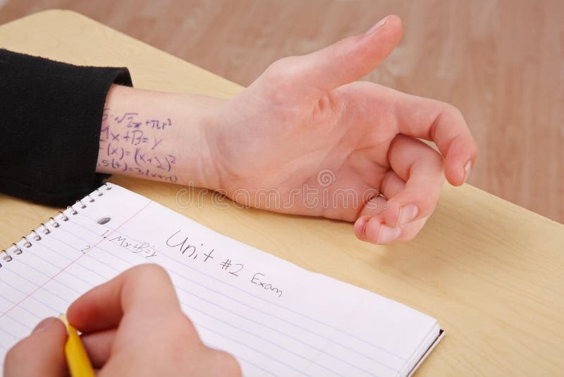 A person is at a desk taking a test and they have the answers written on their wrist. A person is at a desk taking a test and they have the answers written on their wrist