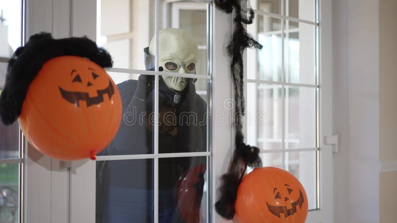Enge buitenaardse wezens die achter een glazen deur lopen en die in de openlucht rondlopen met een halloween jack olantern decorat