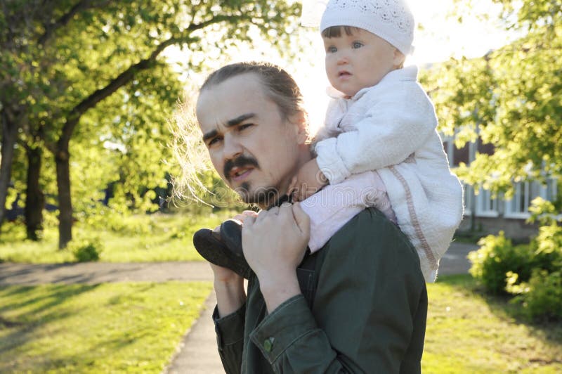 Engendre con el bebé de la hija en hombros que camina en parque en el día soleado Retrato auténtico de la familia fotografía de archivo Engendre con el bebé de la hija en hombros que camina en parque en el día soleado Retrato auténtico de la familia fotografía de archivo