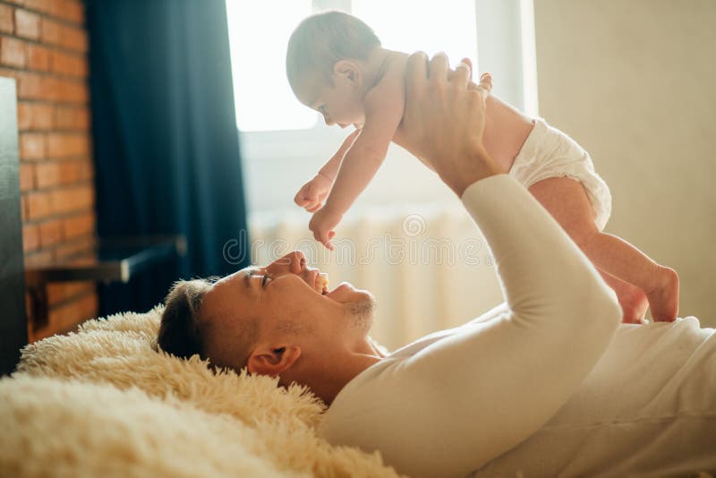 Engendrez le mensonge avec la fille mignonne de bébé sur le lit photographie stock libre de droits Engendrez le mensonge avec la fille mignonne de bébé sur le lit photographie stock libre de droits