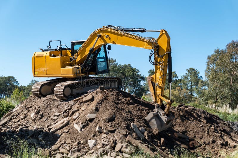 Taming the landfill: Backhoe on top of a gravel mound. Taming the landfill: Backhoe on top of a gravel mound