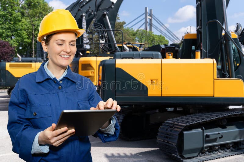 Engenheira de capacete com tablet digital ao lado de escavadoras de construção. imagens de stock