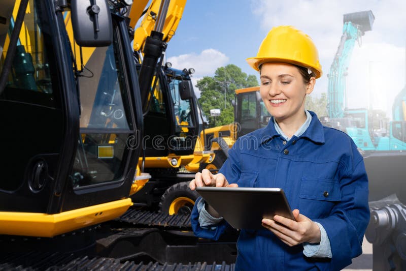Engenheira de capacete com tablet digital ao lado de escavadoras de construção. imagem de stock royalty free