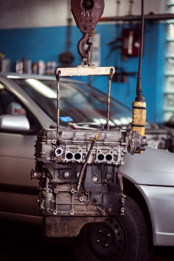 Engine Hanging on Crane Hook on Car Repair Service. Photo of Old Engine