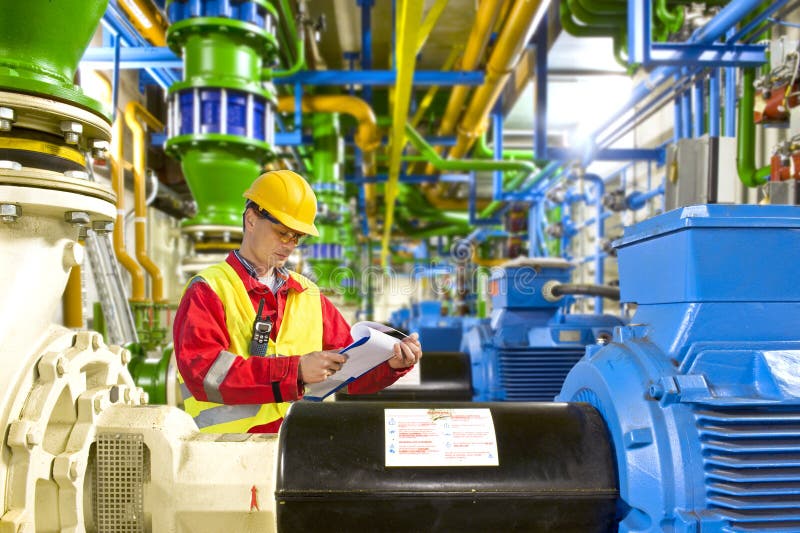 Ingegnere ricerca aty una lista di controllo durante i lavori di manutenzione in un grande industriale sala macchine.