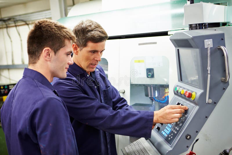 Engineer And Apprentice Using Automated Milling Machine royalty free stock photos Engineer And Apprentice Using Automated Milling Machine royalty free stock photos