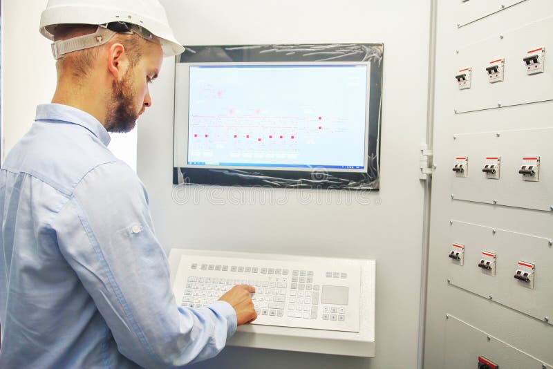 Engineer controls technological equipment from remote control board. Scada system for automation equipment royalty free stock photo