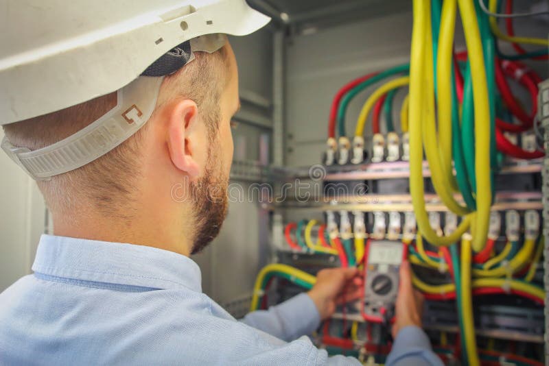 Engineer electric measures multimeter voltage of high-power electrical circuits. royalty free stock photography