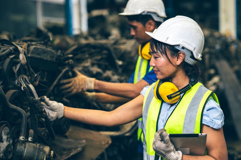 Engineer employee team women worker working together with man work in dirty junkyard old used auto car part warehouse for recycle stock images