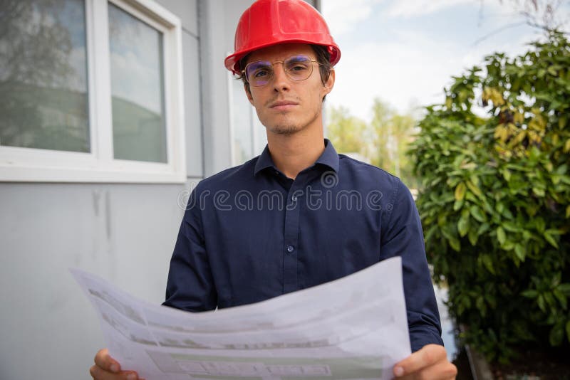 An Engineer with a Floor Plan in Hand Wears a Protective Case on the Construction Site Stock