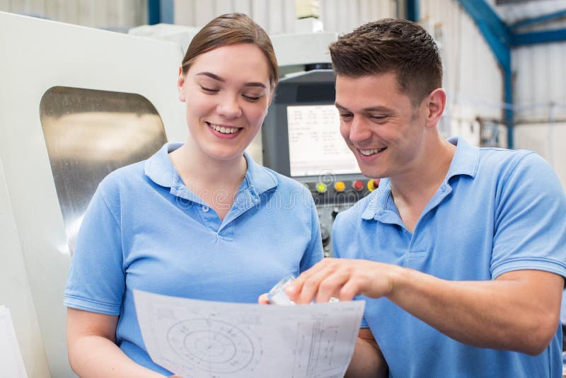 Engineer Instructing Female Apprentice On Use Of CNC Machine royalty free stock photography