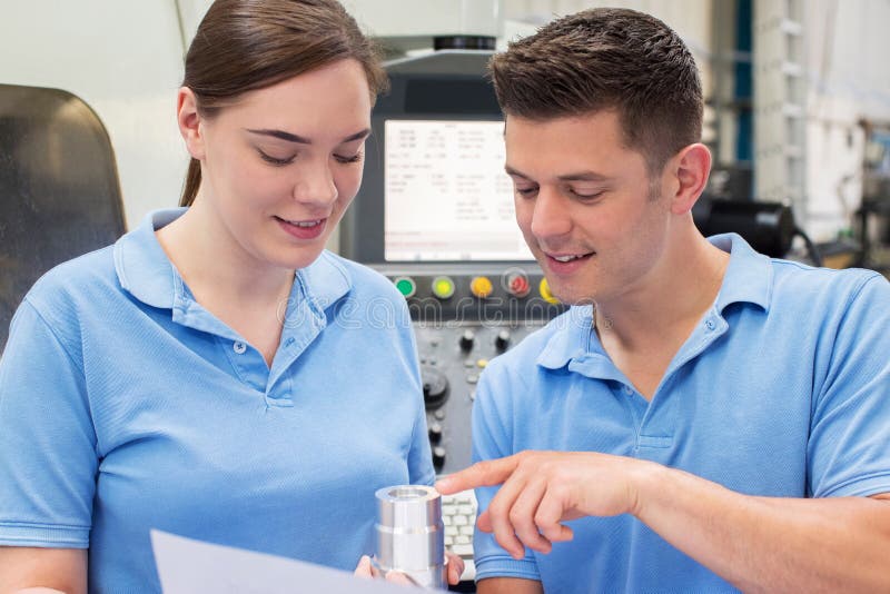 Engineer Instructing Female Apprentice On Use Of CNC Machine stock image