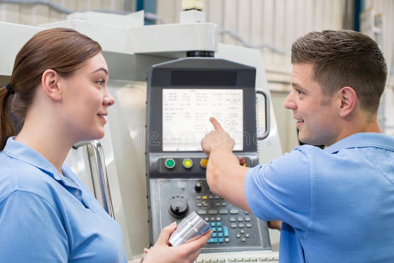 Engineer Instructing Female Apprentice On Use Of CNC Machine stock images