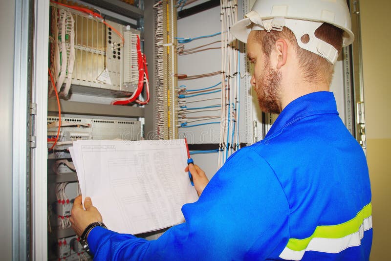 Engineer looks at the electrical drawing on the background of the automation panel royalty free stock photography