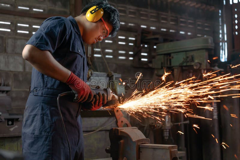 Engineer operating angle grinder hand tools in manufacturing factory - Mechanical engineering student using power tool with hot royalty free stock photography
