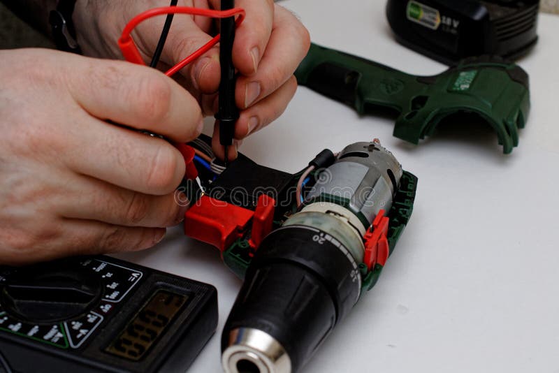 Engineer Repairs a Broken Screwdriver. Checks Contacts with a Tester
