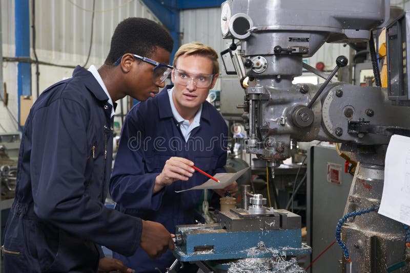 Engineer Showing Apprentice How to Use Drill In Factory