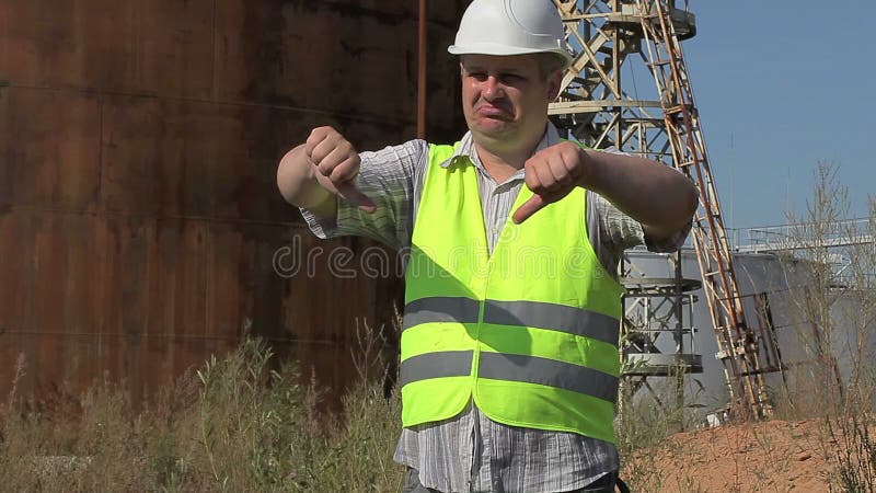 Engineer showing thumbs down near to the tanks